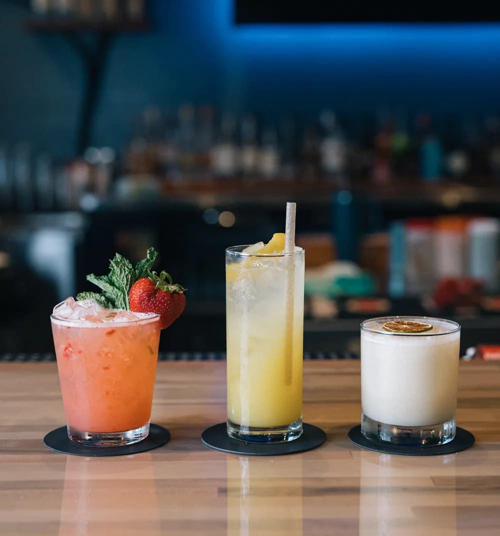 Three Sweet Fish craft cocktails lined up on the bar top.